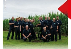 Baumpflanz_Challenge_Gruppenfoto.jpg Auf dem Bild ist ein Gruppenfoto unserer Kameradinnen und Kameraden in Tagesdienstkleidung zu sehen. Sie stehen um einen frisch gepflanzten Baum herum