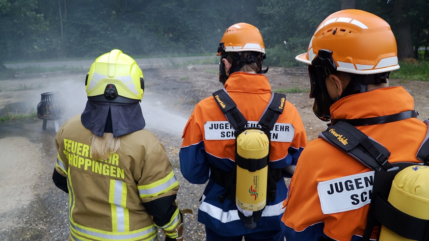 Jugendfeuerwehr 1 Zwei Mitglieder der Jugendfeuerwehr löschen ein Feuer mit einem Strahlrohr, während sie mit Atemschutzgeräten ausgerüstet sind. © Freiwillige Feuerwehr Schöppingen